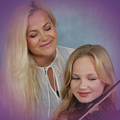 Frau und Mädchen mit Geige lächeln gemeinsam