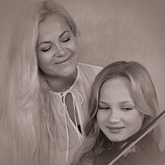 Frau und Mädchen mit Geige lächeln gemeinsam